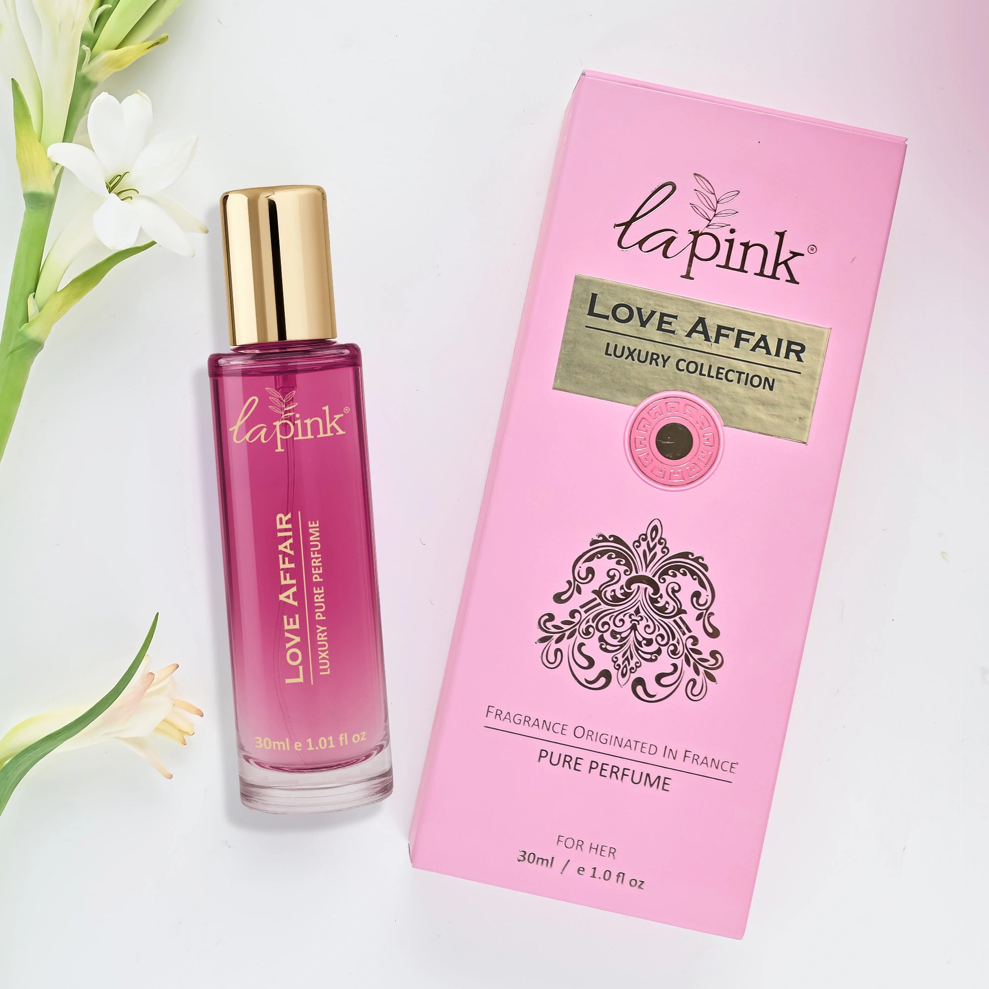 La Pink Love Affair perfume bottle and packaging with flowers on a light background