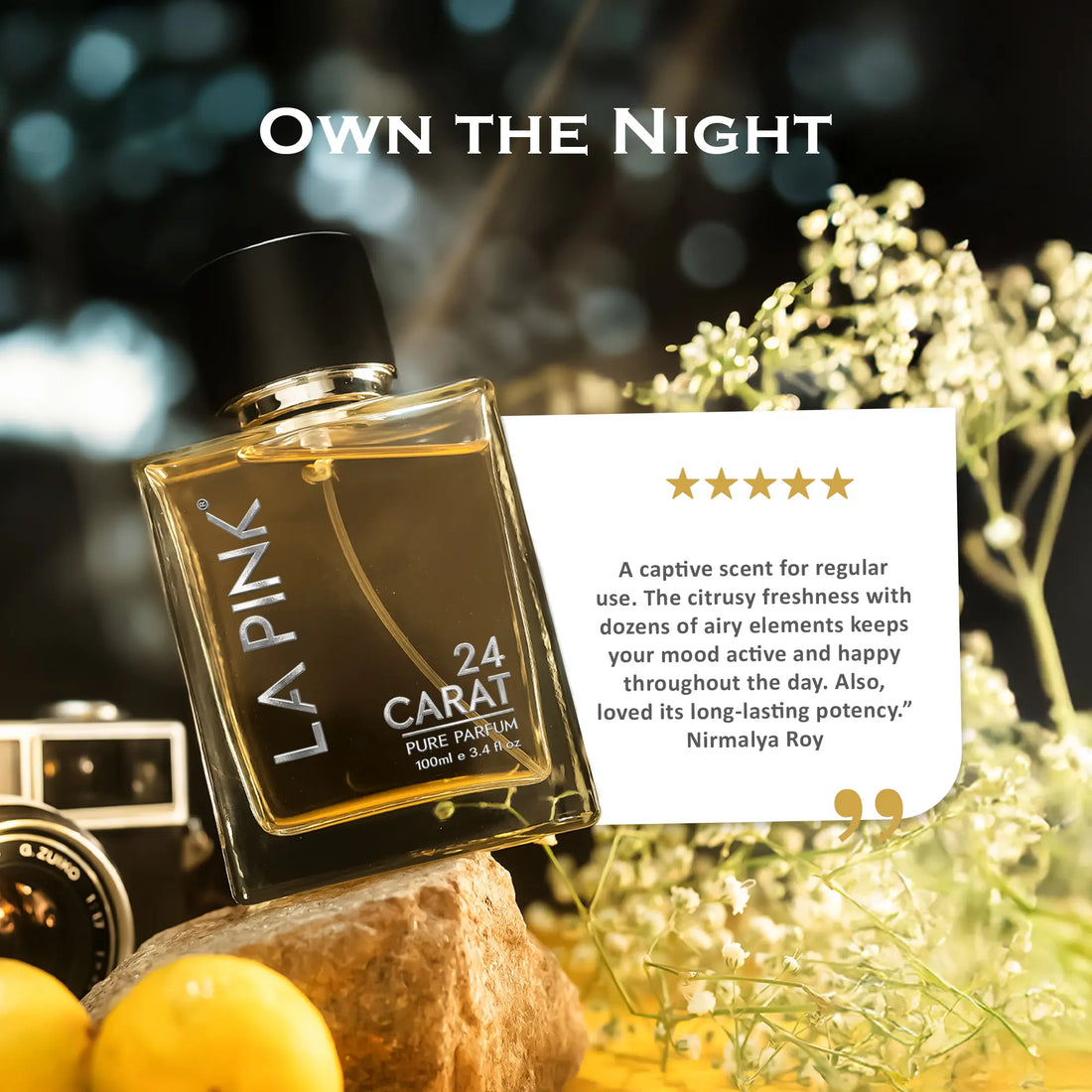 LA PINK 24 Carat Pure Fragrance bottle displayed on a rock with lemons and white flowers, alongside a star review card and the text &
