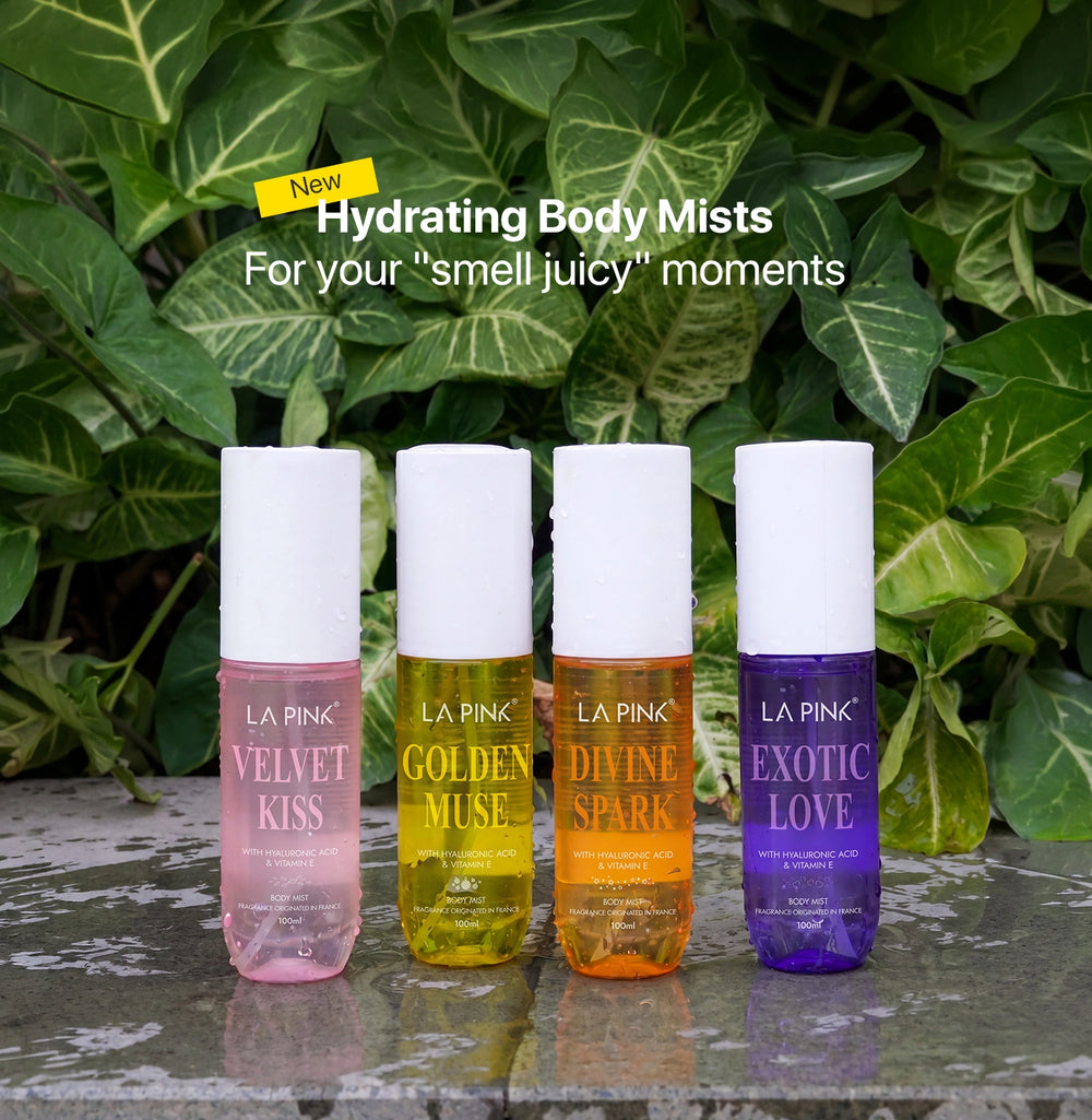 Four bottles of LA Pink hydrating body mists with colorful labels against a green leafy background.