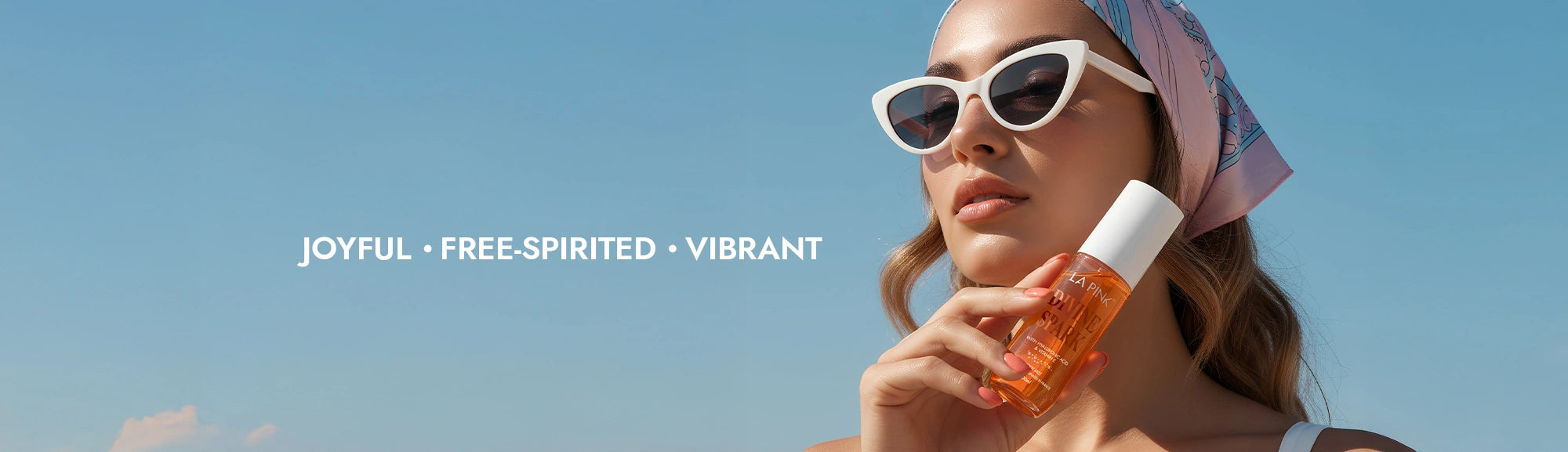 Woman holding a bottle of sunscreen with a clear blue sky background and text 'JOYFUL • FREE SPIRITED • VIBRANT'.