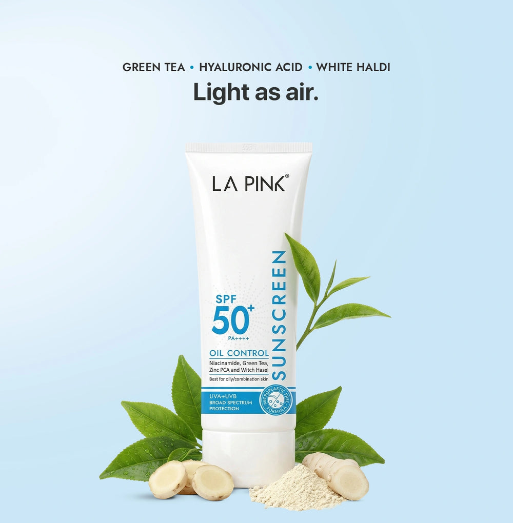 LA Pink sunscreen tube with green tea leaves and white haldi on a light blue background