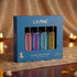 LA PINK Silver Collection 4-piece perfume discovery pack in a blue box, featuring four distinct colored bottles (pink, purple, blue, and yellow) on a patterned table runner with warm candlelit background.

