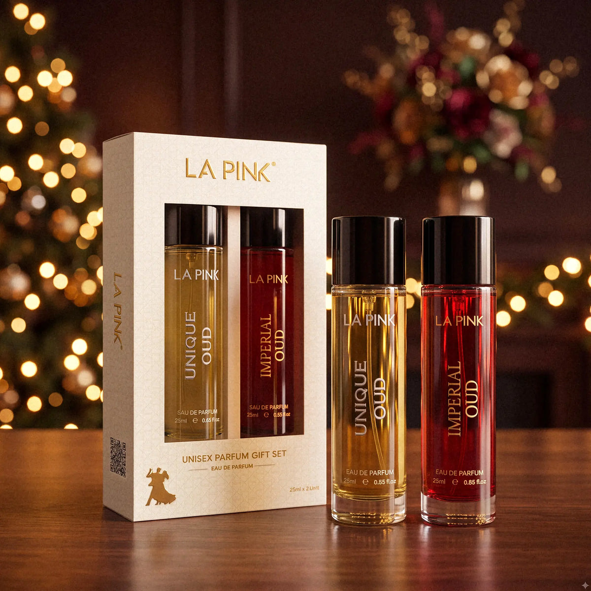 LA PINK Unisex Parfum Gift Set featuring a white box with two bottles inside and two individual bottles (Unique Oud in amber and Imperial Oud in red) on a wooden table with festive blurred lights in the background.