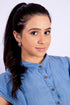 Woman with a ponytail wearing a blue shirt against a white background